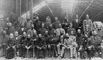        ::         ,      .      ,  ,      
(British workers in a mashine shed at Hughesovka, 1890s. John James Hughes is seated 2nd from right, front row, with one of his brothers sitting behind him. Also in the photograph are David Waters, William Lethbridge, William Lewis, and William Waters)
